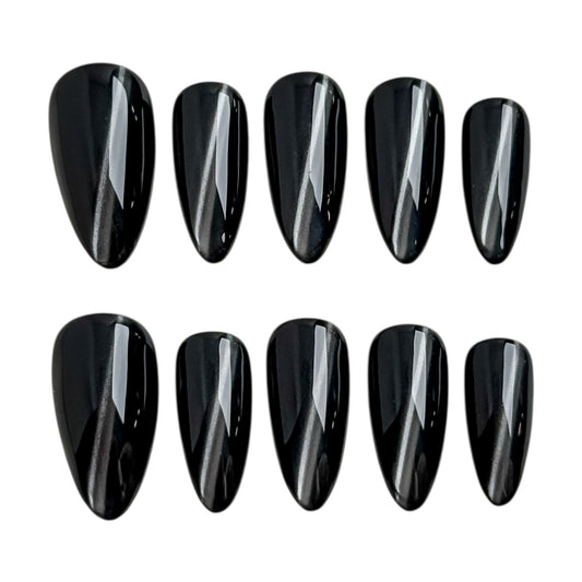 Ongles press-on noir profond avec effet œil de chat diagonal, finition ultra brillante et forme amande élégante