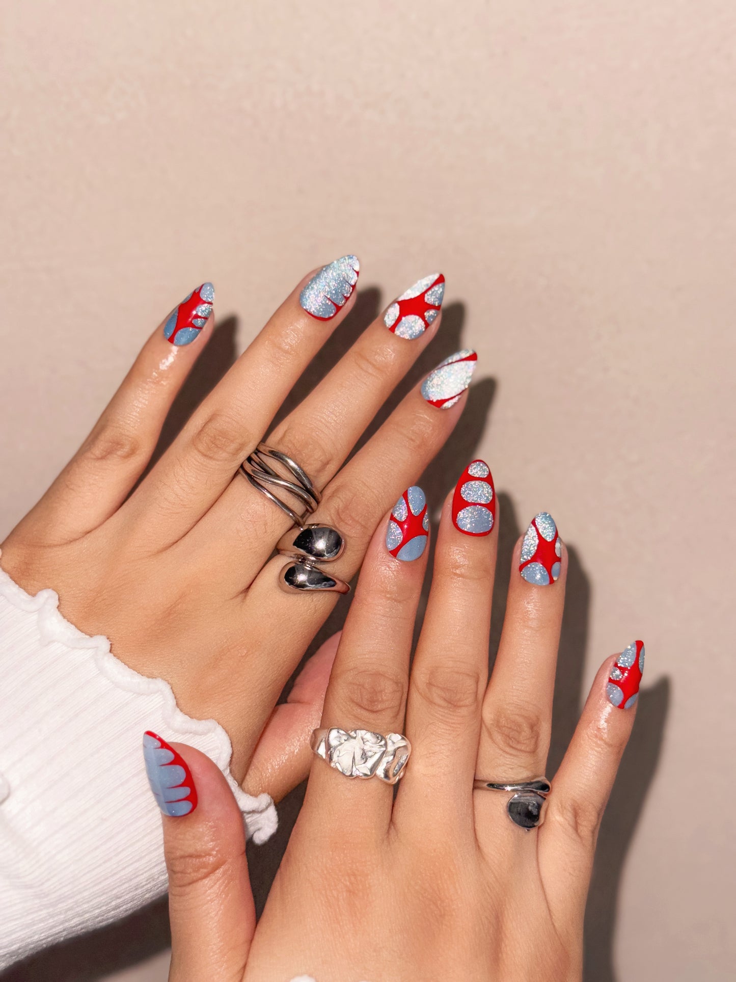Ongles réutilisables Nailmusee Die With a Smile avec motifs géométriques rouges sur fond argenté