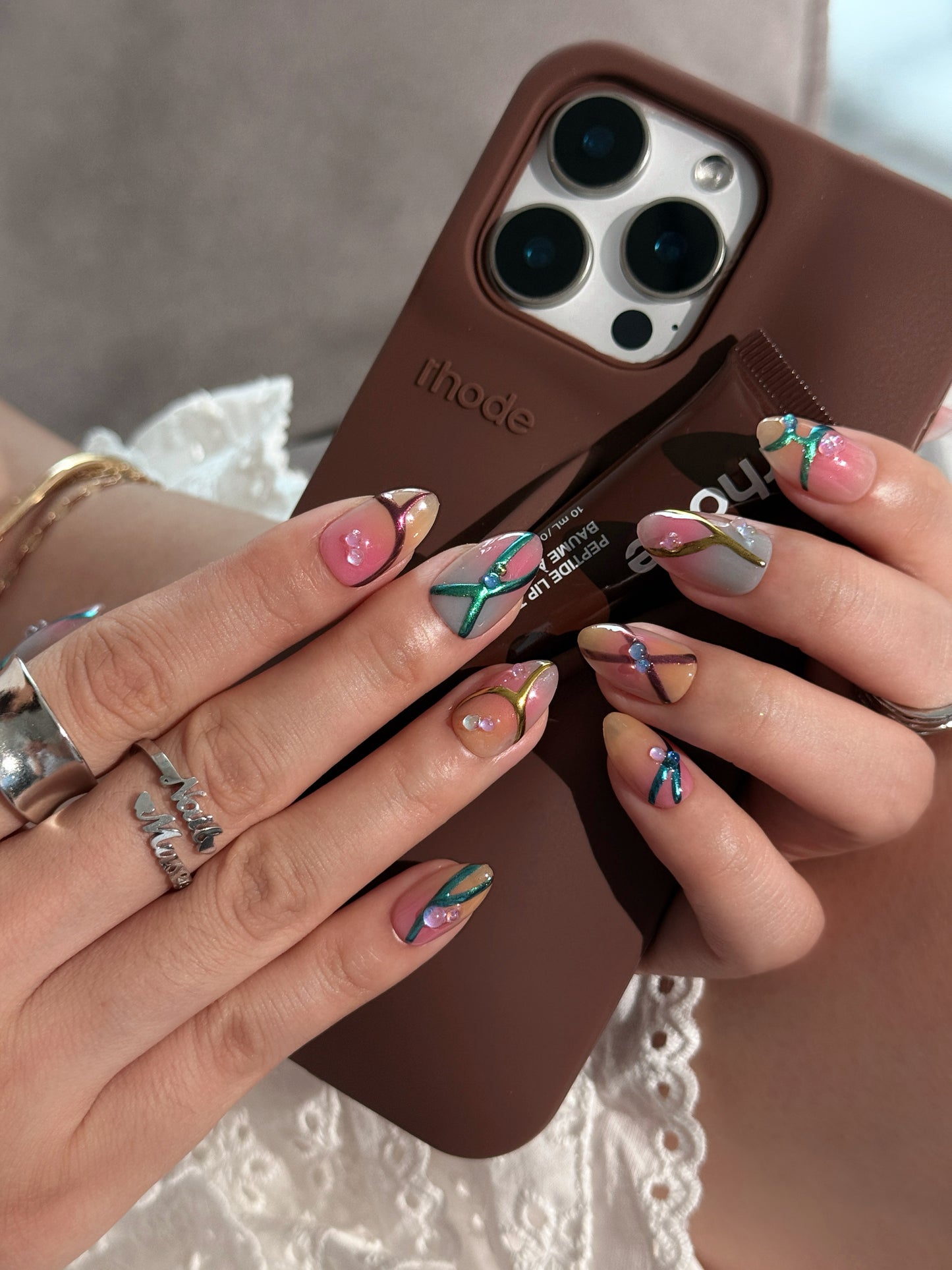Press-on nails Bonbon avec dégradé rose et caramel, lignes métalliques en relief et finitions artisanales.