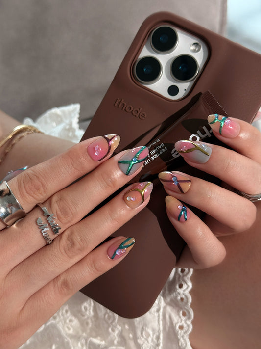 Press-on nails Bonbon avec dégradé rose et caramel, lignes métalliques en relief et finitions artisanales.