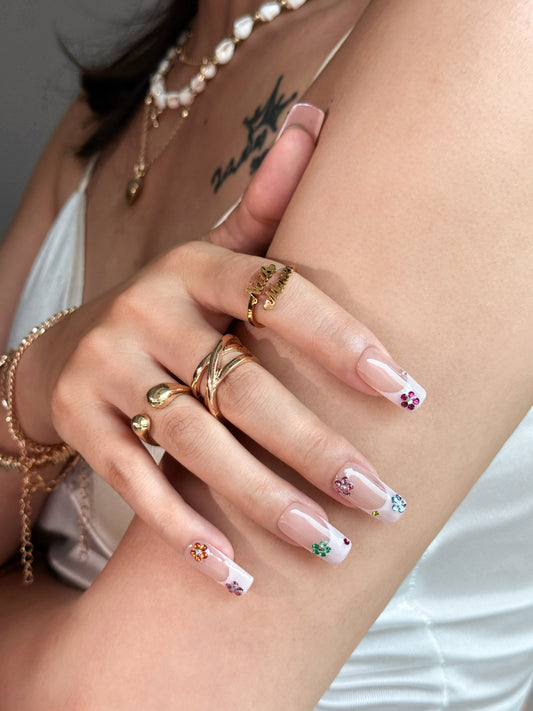 Press-on nails Fleuron portés, avec French, fleurs en strass colorés et forme carrée longue.