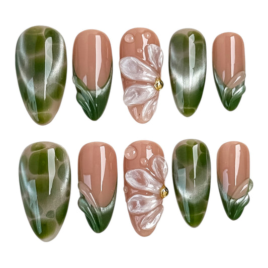 Faux ongles artisanaux Forêt Perlée de NAILMUSEE avec effet cat eye vert, fleur 3D nacrée et détails végétaux.