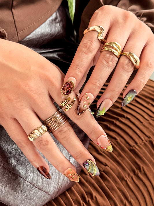 Amber Jewel press on nails portés, tons ambre, brun et vert olive avec bijoux dorés