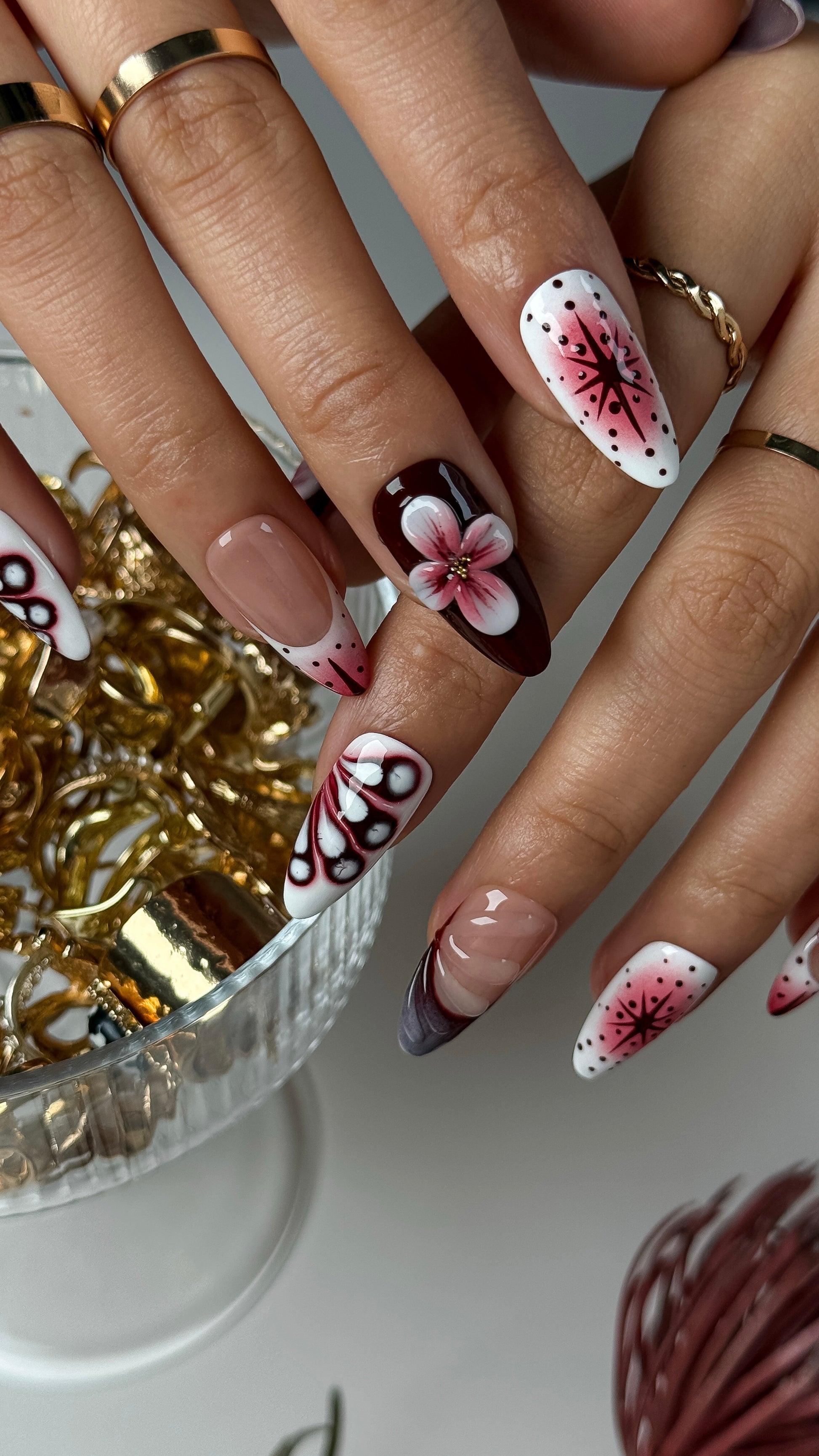 détails nail art fleurs sur faux ongles rouge et nude, style naturel et élégant

