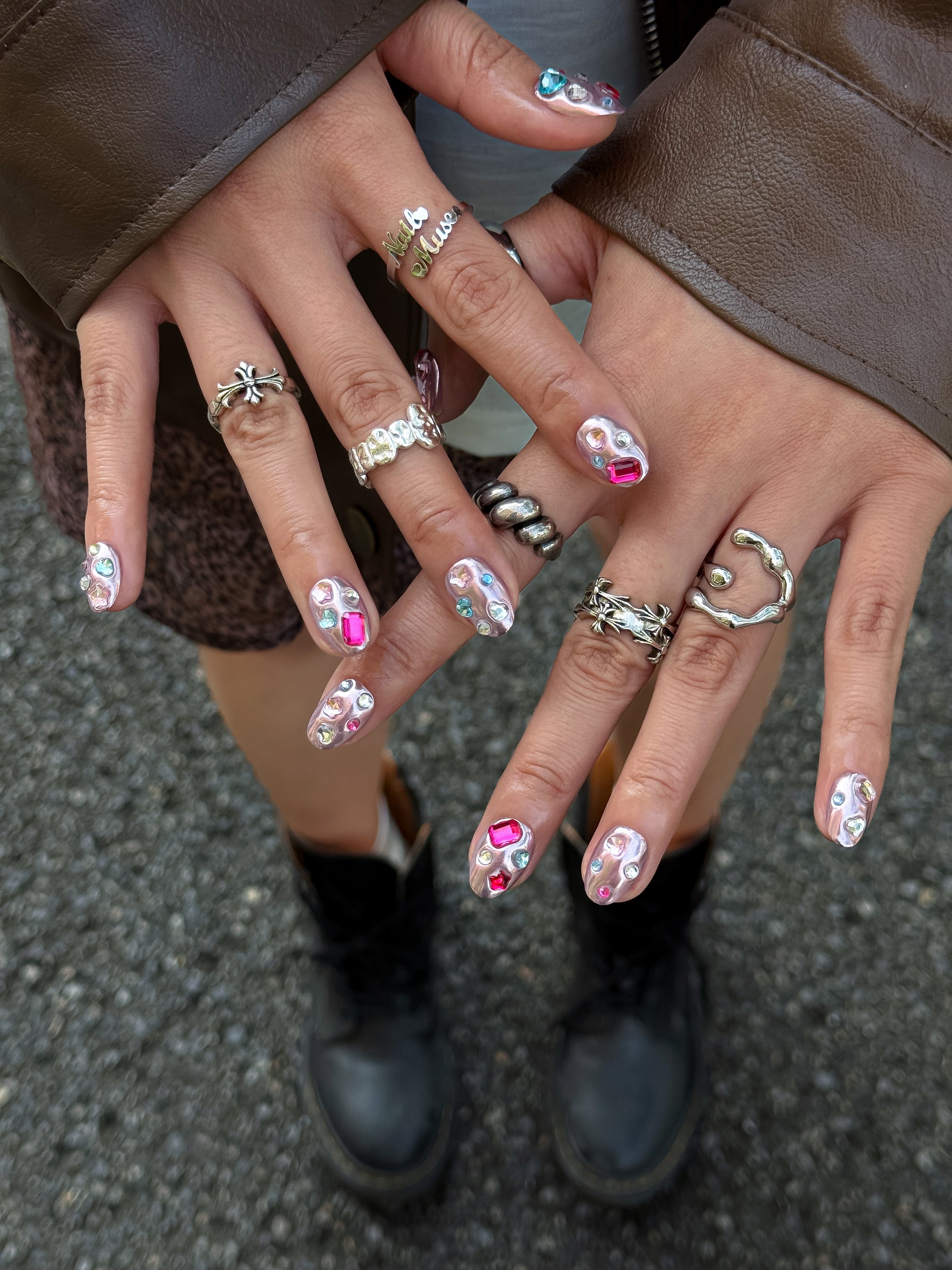 Close-up of NailMusee Chrome Candy press-on nails featuring glossy pink chrome and multicolor jewel details