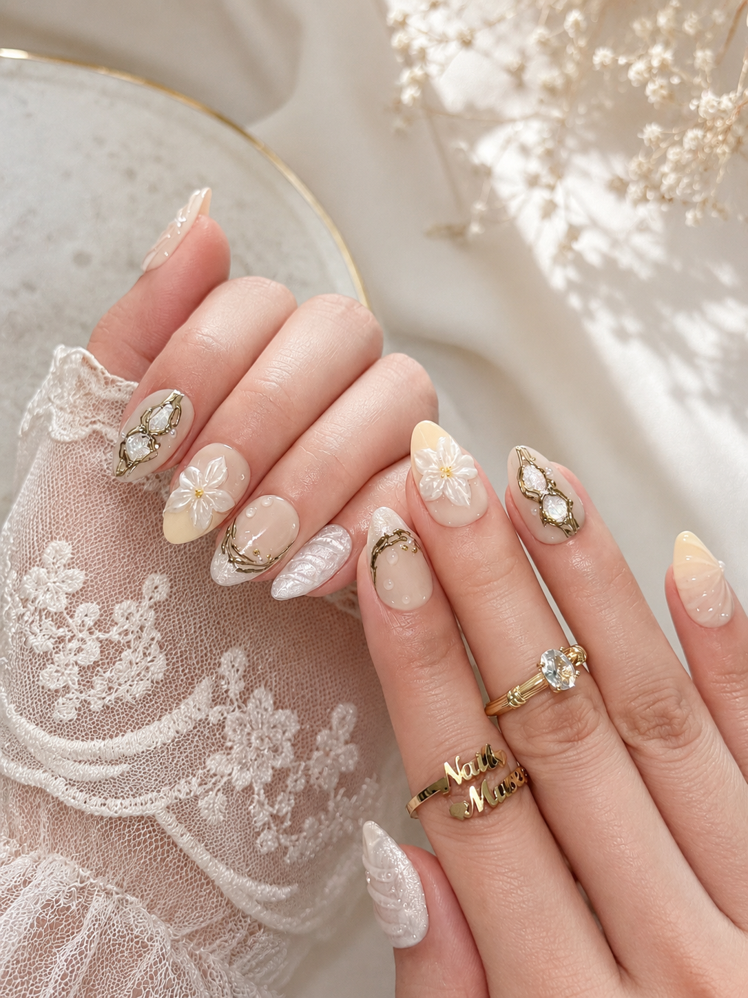 Model wearing Ivory Relique press-on nails by Nail Musee with sculpted white flowers, pearlescent textures, and antique gold detailing.
