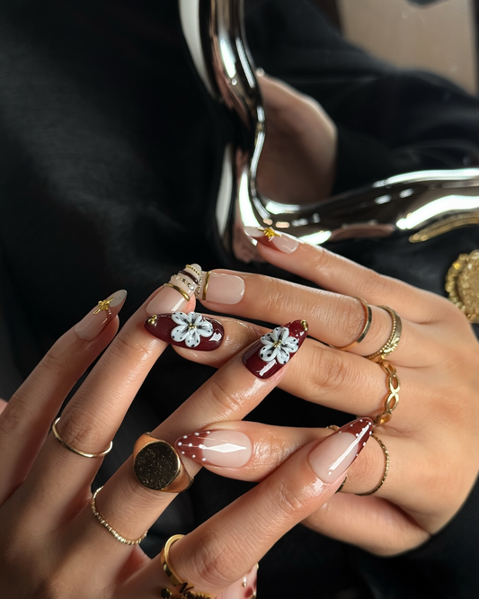 Ongles press-on élégants nude et bordeaux portés sur la main