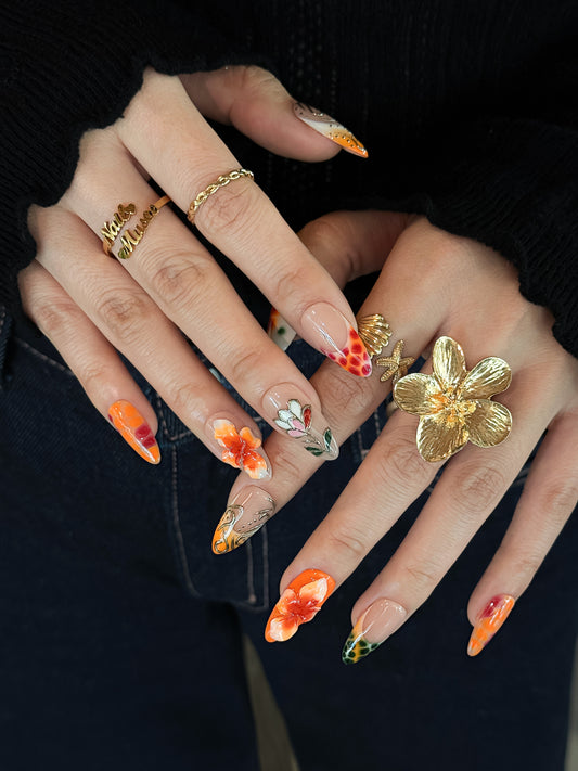 press on nails orange floral avec détails délicats et effet brillant.