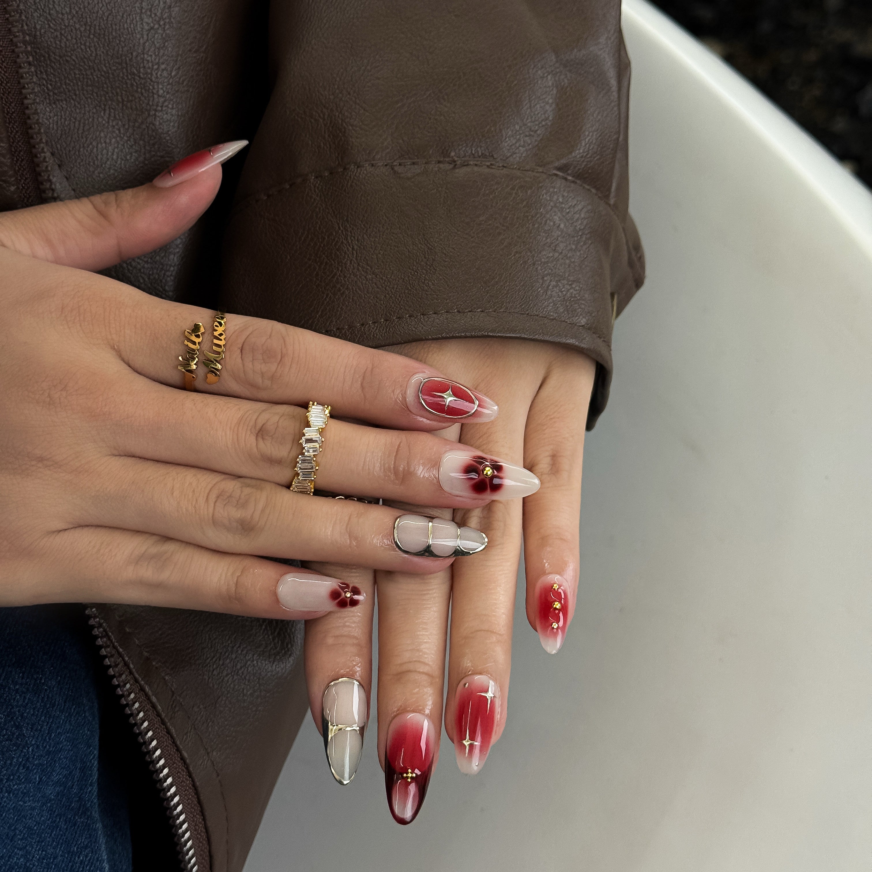 Model wearing Rouge Bohème press-on nails with soft red gradient and gold metallic details