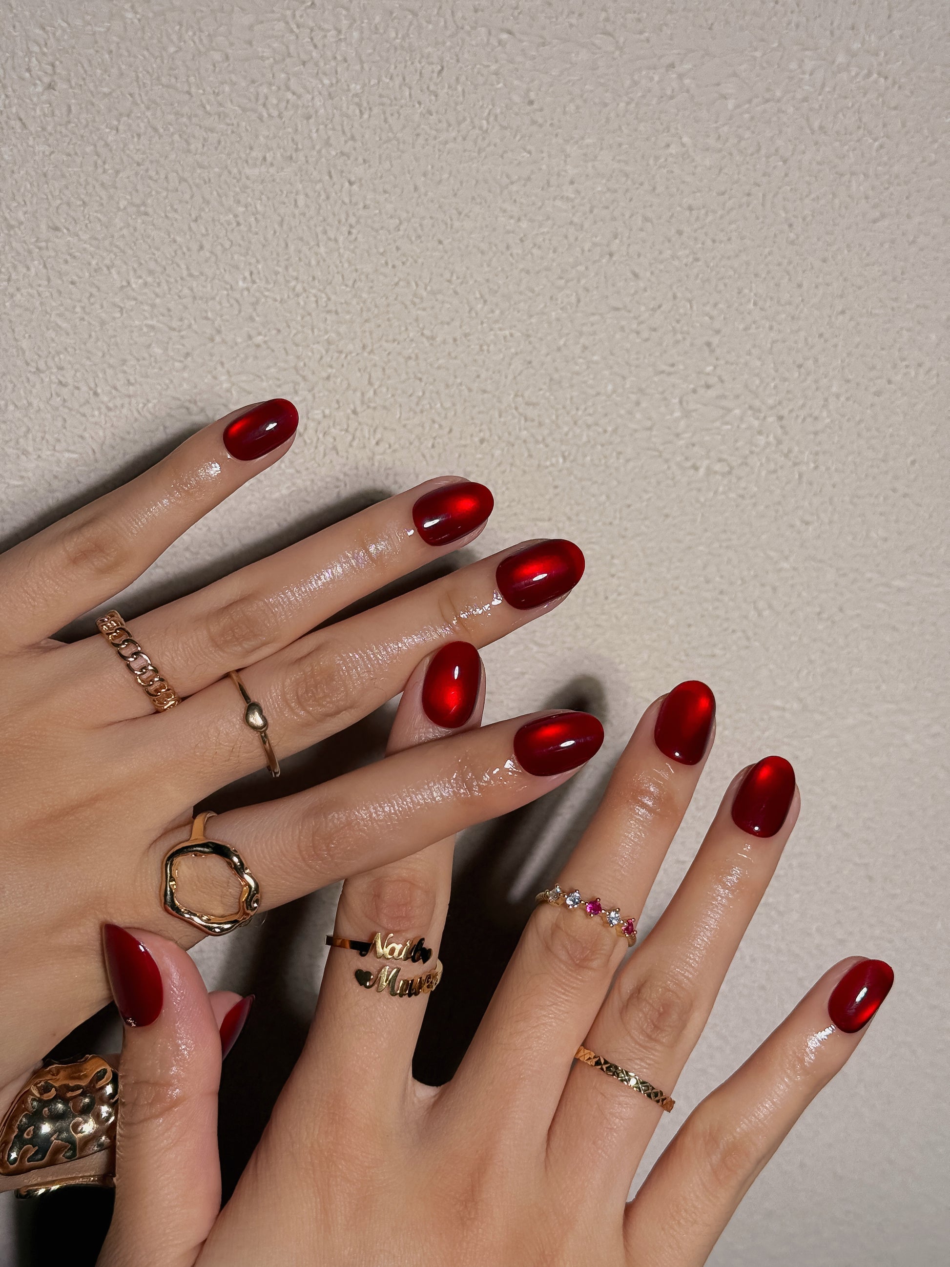 Ongles courts arrondis rouges avec effet perle de verre et cat eye