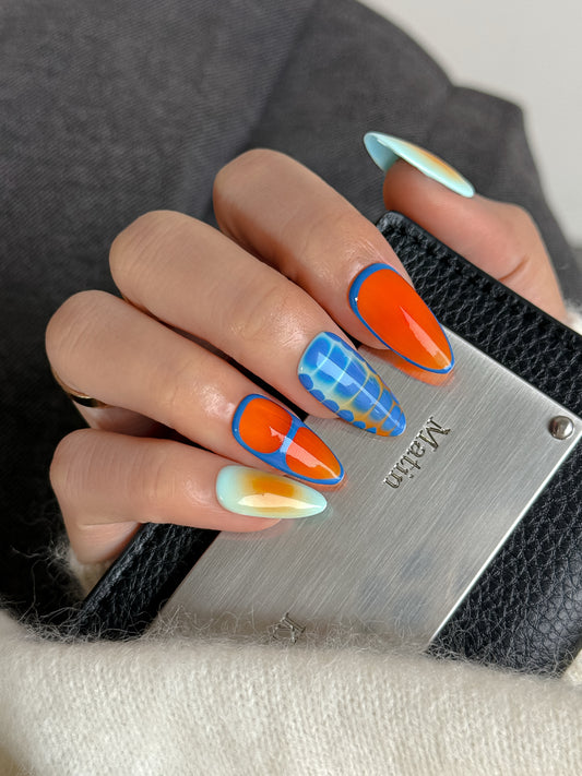 faux ongles colorés portés sur main avec design bleu et orange effet brillant.