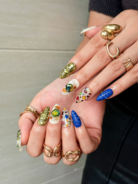Vitrail d’Or press on nails portés, nail art bleu et coloré avec détails dorés et effet bijou
