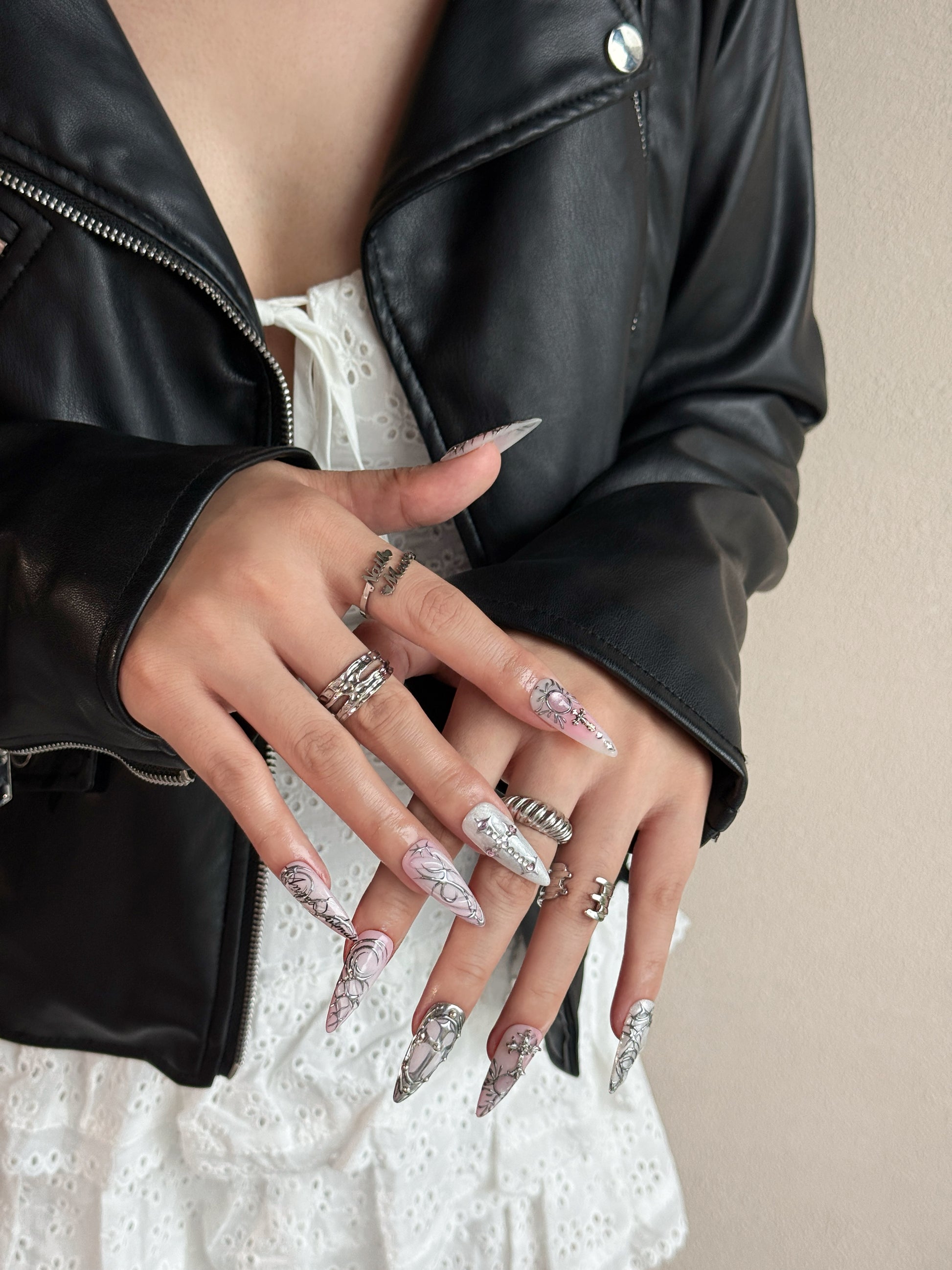 Press-on nails Relique Rose portés, avec dégradé rose, détails chrome en relief et forme stiletto longue.